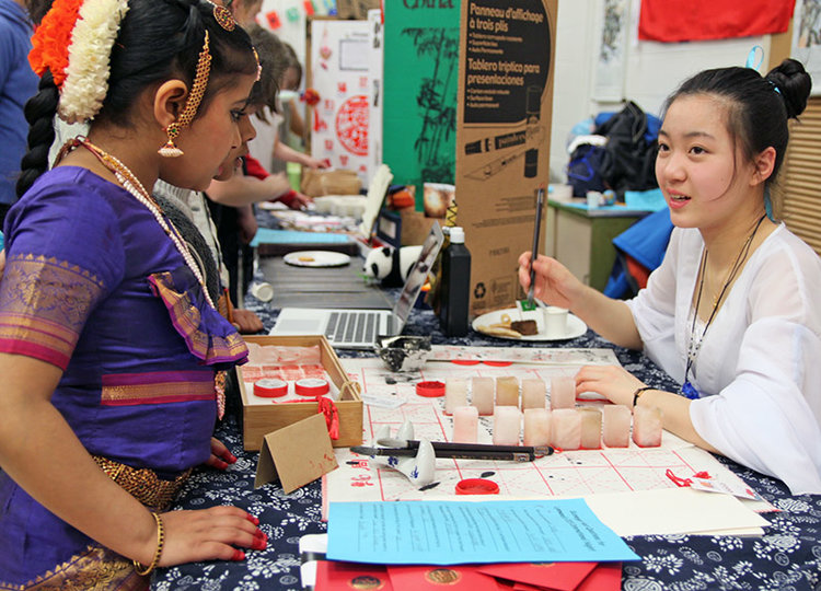 Ruby Yuan, right, prepares to write in Chinese calligraphy the names of students taking part in the first-ever International Night at Lynnwood Elementary School on April 12.