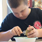 Tyler Harnett spoons out the insides of a potato to make loaded baked potatoes as part of the Junior Chef Cook-Off at the Berne Library.