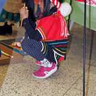 A small child wearing Taiwanese clothing finds a private spot beneath an informational display from which to watch the performances. 